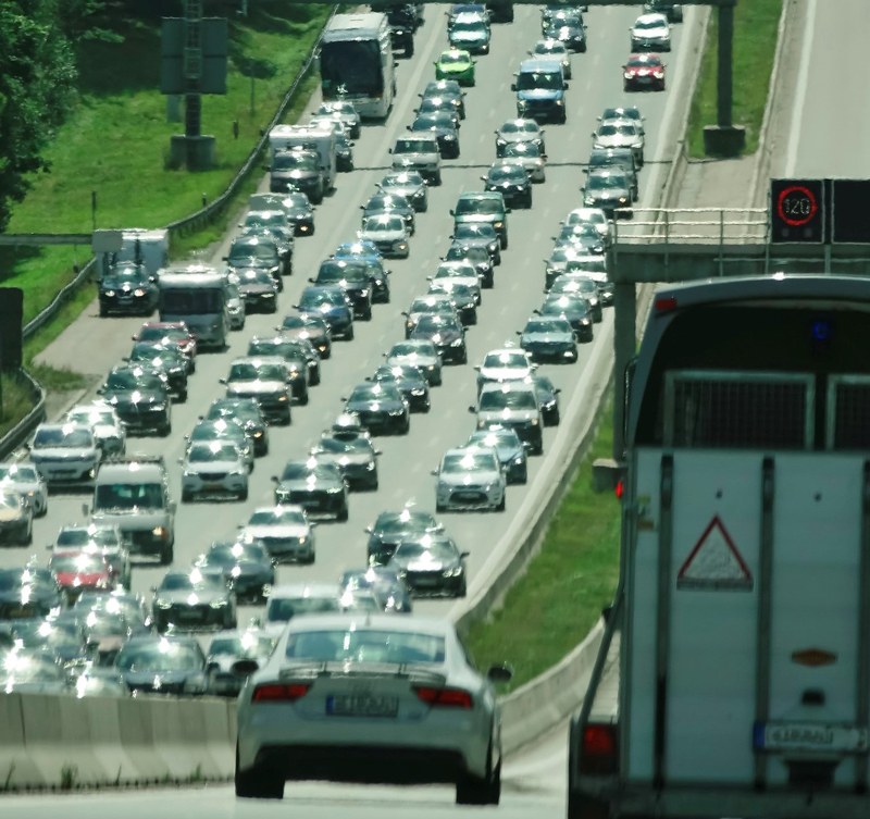 Picture of a four-lane traffic with cars ascending on the left-side; on the right, the back of a van and a saloon car is in focus going downhill.