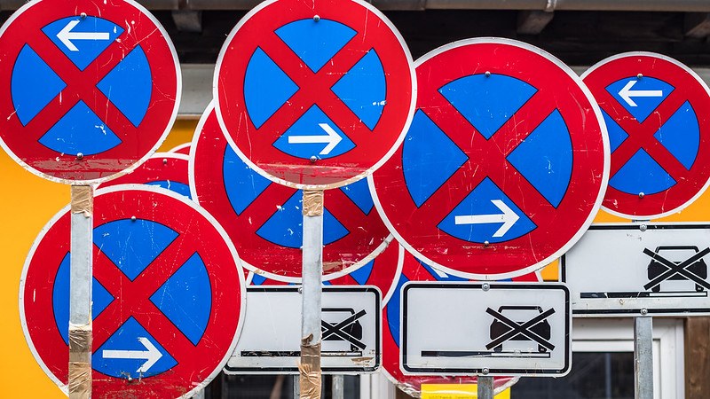 Image of traffic signs showing no-stopping with arrows pointing left or right and prohibiting vehicles.